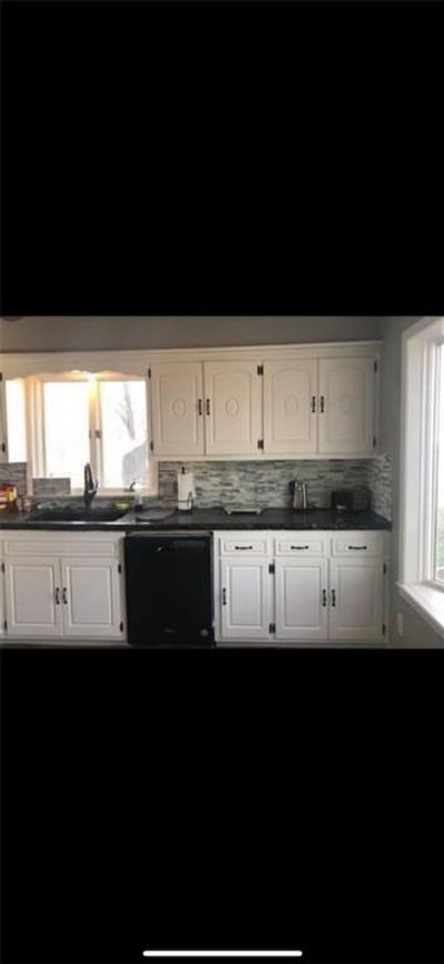 Kitchen with white cabinetry, black dishwasher, a healthy amount of sunlight, and sink | Image 2