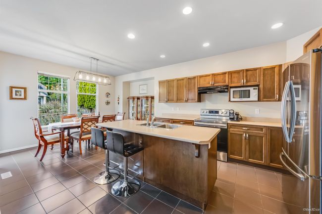 Kitchen featuring under cabinet range hood, light countertops, brown cabinets, stainless steel appliances, and a sink | Image 5