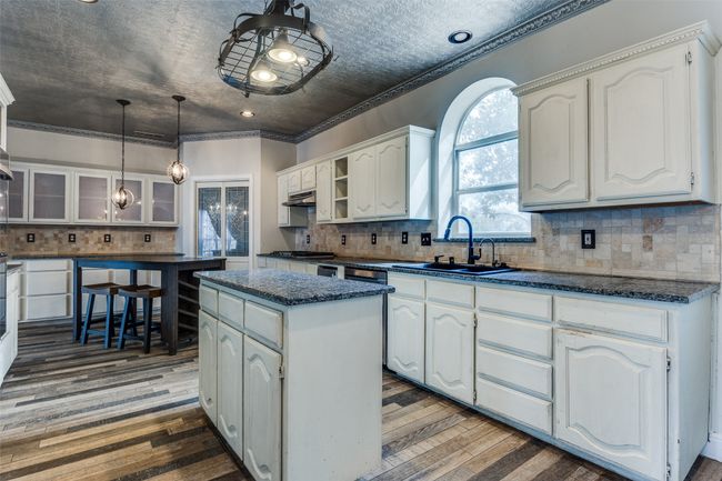 Kitchen with a center island, white cabinetry, glass insert cabinets, and wood finished floors | Image 13