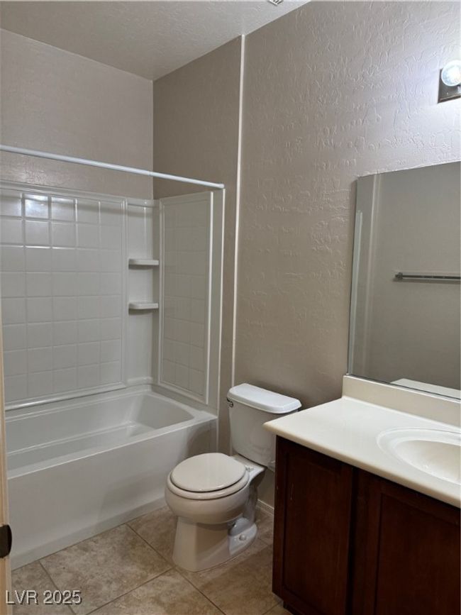 Bathroom with a textured wall, vanity, shower / bathtub combination, and tile patterned floors | Image 14