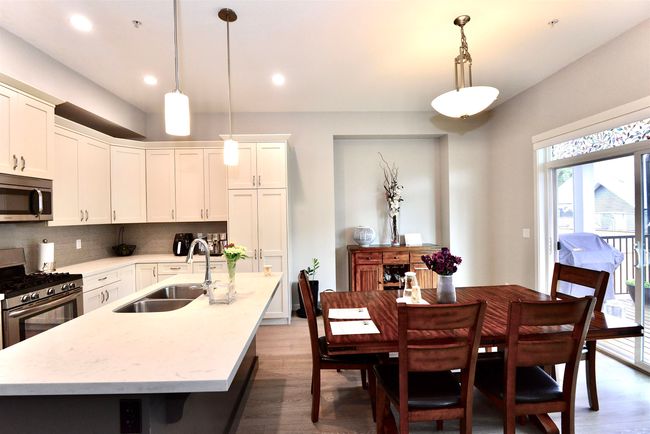Kitchen with stainless steel appliances, wood finished floors, backsplash, a center island with sink, and recessed lighting | Image 19