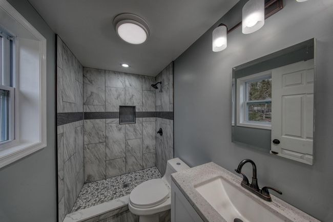 Bathroom featuring a tile shower, toilet, and vanity | Image 17