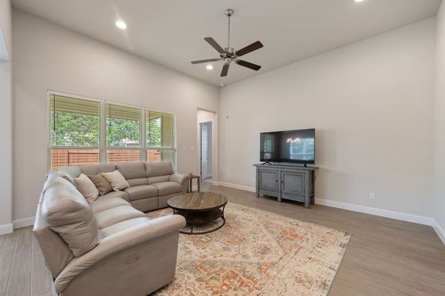 Living room featuring ceiling fan, wood finished floors, recessed lighting, baseboards, and a high ceiling | Image 5