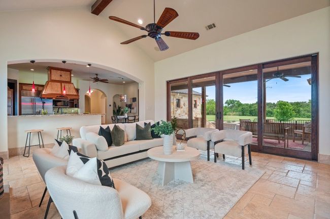 Living room featuring expansive sliders, beamed ceiling, and arched walkways. | Image 11