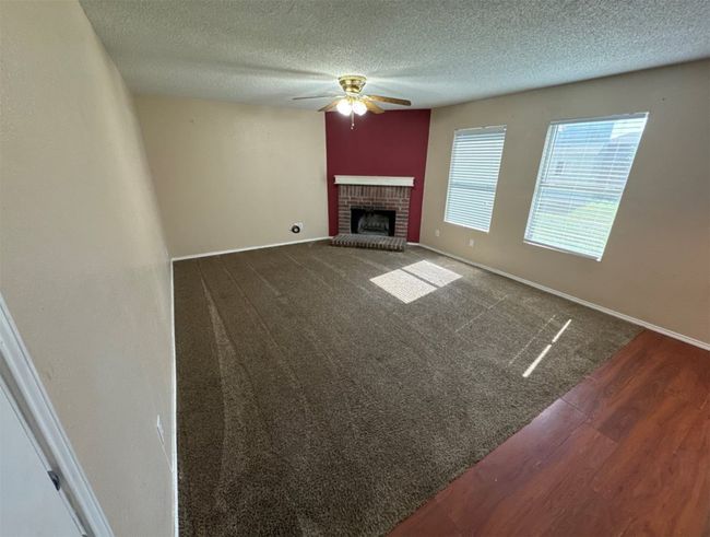 Unfurnished living room featuring ceiling fan, a fireplace, carpet floors, and a textured ceiling | Image 7