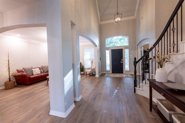 Entrance foyer with arched walkways, a high ceiling, stairs, hardwood / wood-style floors, and ornamental molding | Image 5