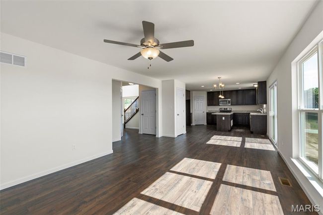 Unfurnished living room featuring dark wood-style flooring, a ceiling fan, stairway, a chandelier, and recessed lighting | Image 11