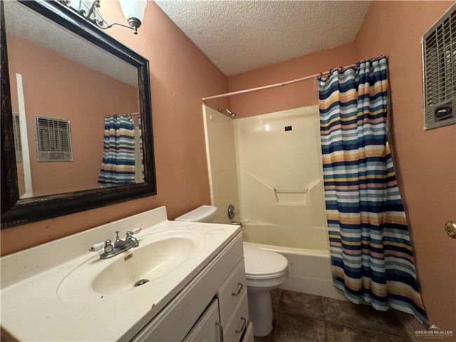 Full bathroom featuring toilet, vanity, a textured ceiling, tile patterned floors, and shower / bathtub combination with curtain | Image 8