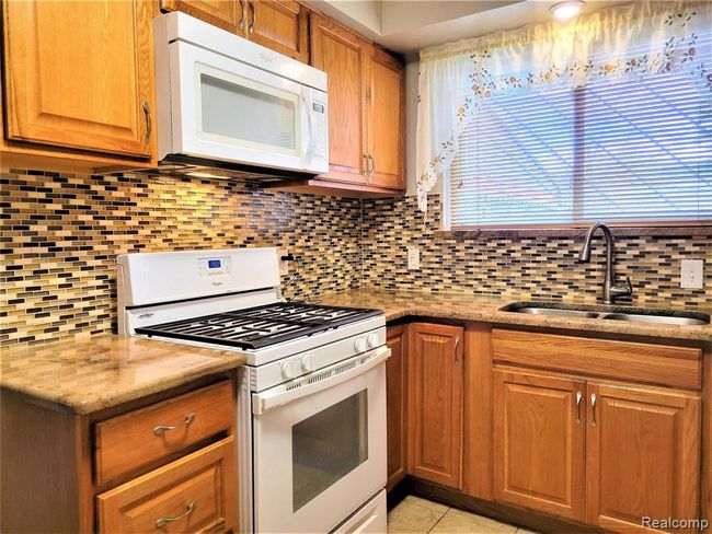 Updated kitchen with granite, glass backsplash and ceramic floor | Image 9