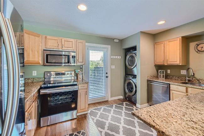 Kitchen with granite counters, stainless appliances and stacked washer/dryer. | Image 5