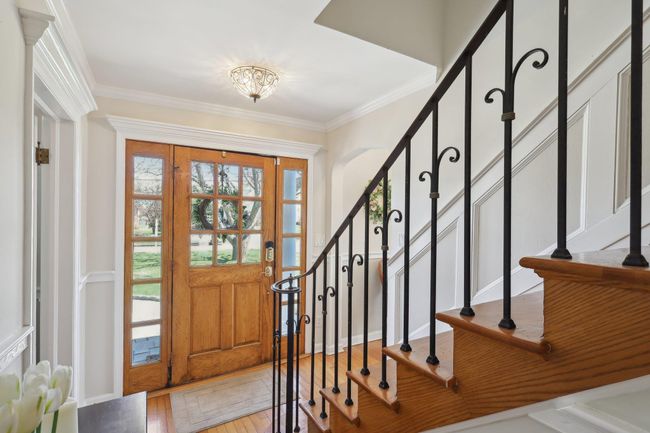 Entryway with crown molding, light wood finished floors, and stairs | Image 6