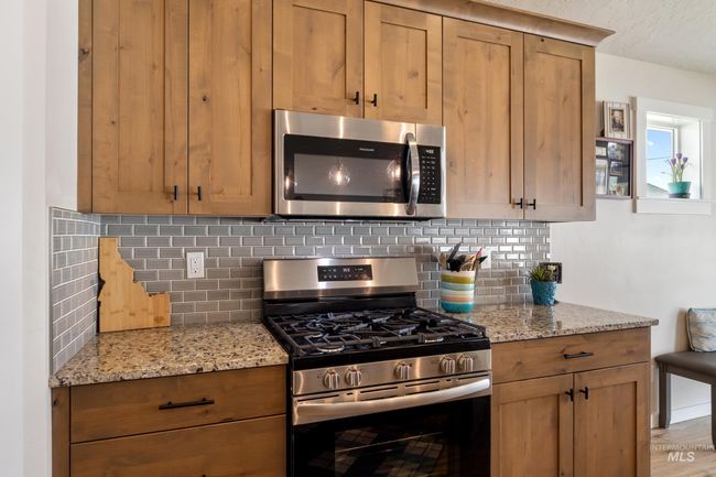 Kitchen featuring appliances with stainless steel finishes, backsplash, and light stone countertops | Image 5