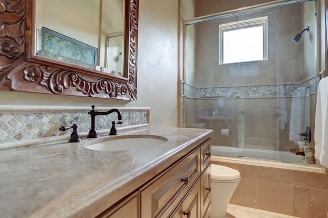 Fourth bedroom bathroom has tub/shower limestone counter, mosaic backsplash. | Image 36