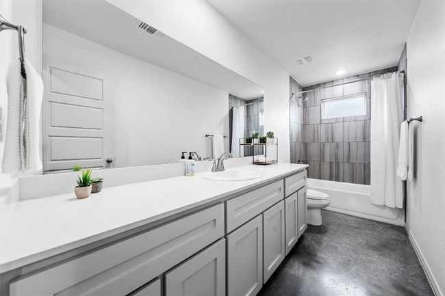 Full bathroom featuring visible vents, toilet, vanity, concrete flooring, and shower / bath combo with shower curtain | Image 17