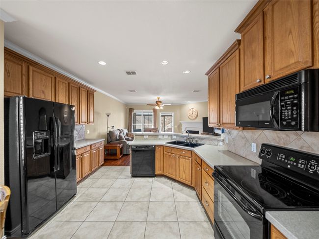 Kitchen featuring light countertops, visible vents, black appliances, and light tile patterned flooring | Image 8