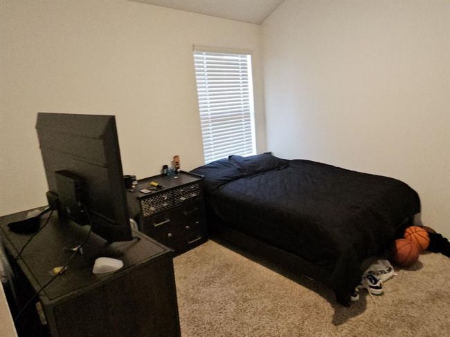 Cozy bedroom with plush carpeting, large window, and space for a full-sized bed and work-from-home setup. | Image 5