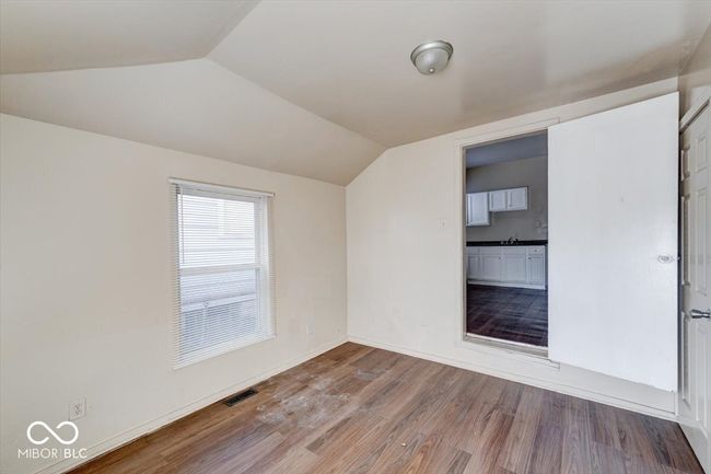 additional living space with baseboards, visible vents, wood finished floors, and vaulted ceiling | Image 16
