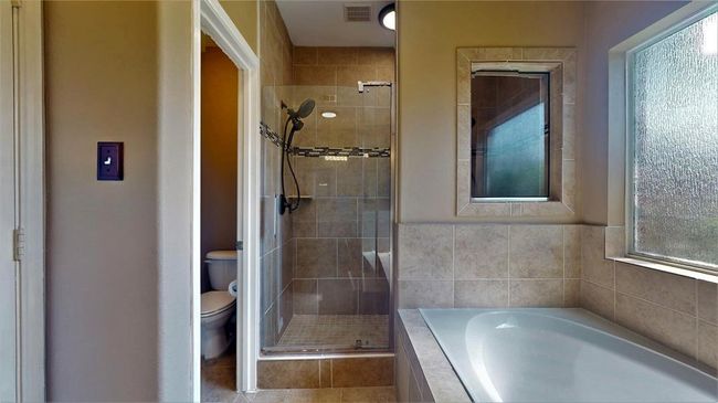 Updated in 2021, the primary bathroom features double sinks, a luxurious jacuzzi tub with steps, a dual shower-head system, and a large wall mirror. | Image 26