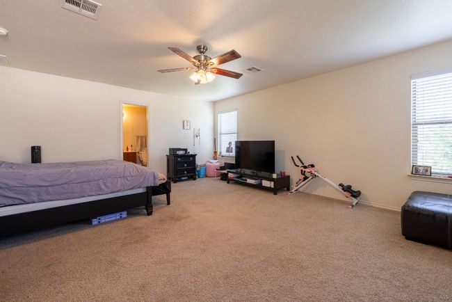 Bedroom featuring light carpet, ceiling fan, and ensuite bath | Image 9