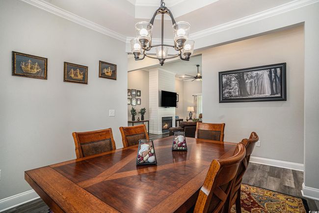 Dining room with a chandelier, a fireplace, wood finished floors, baseboards, and crown molding | Image 8