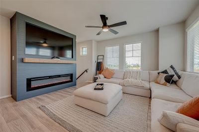 Experience the spacious living room on the second floor of this three-story home. Featuring ample lighting, sleek flooring with no carpet, and a stylish TV wall unit with an electronic fireplace, this inviting space is perfect for relaxation and entertainment. | Image 2