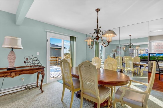 Carpeted dining space featuring beamed ceiling, baseboard heating, and an inviting chandelier | Image 9