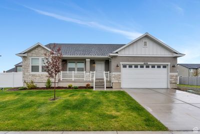 Ranch-style home with a front yard, a porch, and a garage | Image 1