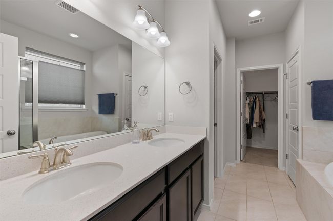 Dual vanities, double walk-in closets, and tile flooring in the primary bathroom. | Image 17