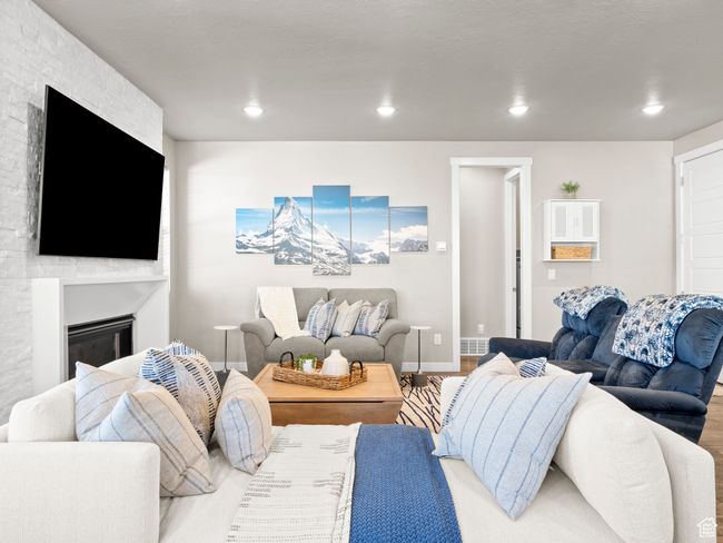 Living area with a glass covered fireplace, wood finished floors, and recessed lighting | Image 6