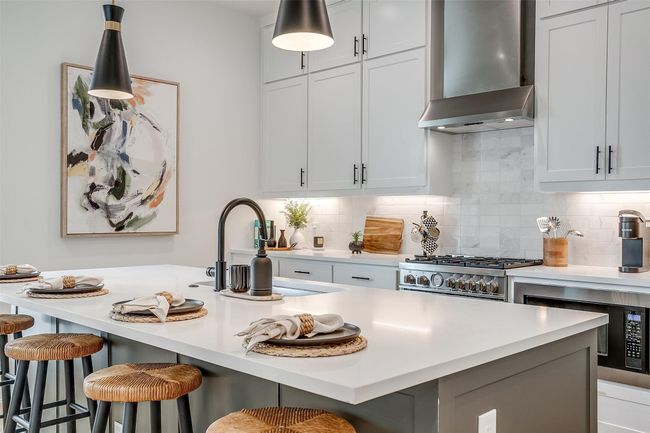 Kitchen featuring wall chimney range hood, light countertops, and a breakfast bar | Image 6