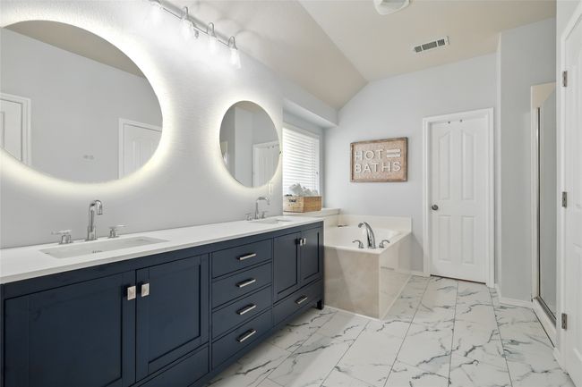 Bathroom featuring double vanity, a garden tub, marble finish floors, and lofted ceiling | Image 26