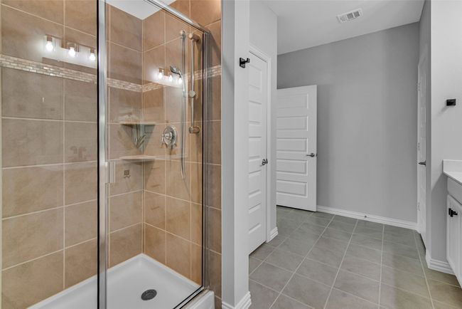 Full bathroom featuring vanity, tile patterned floors, baseboards, a shower stall, and visible vents | Image 21