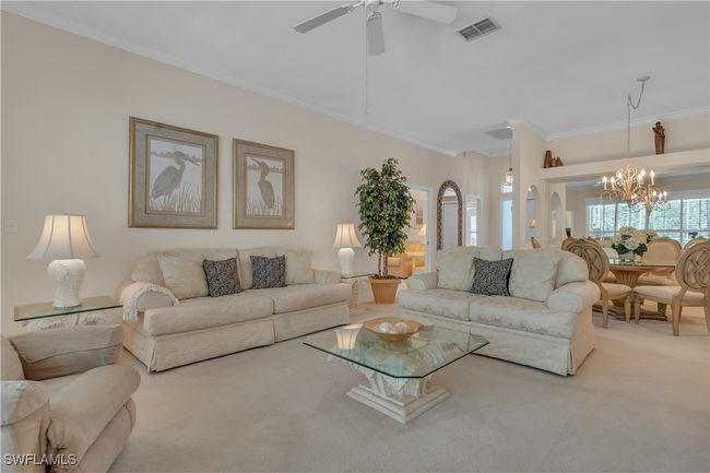 Living room featuring carpet, crown molding, a chandelier, and a ceiling fan | Image 4