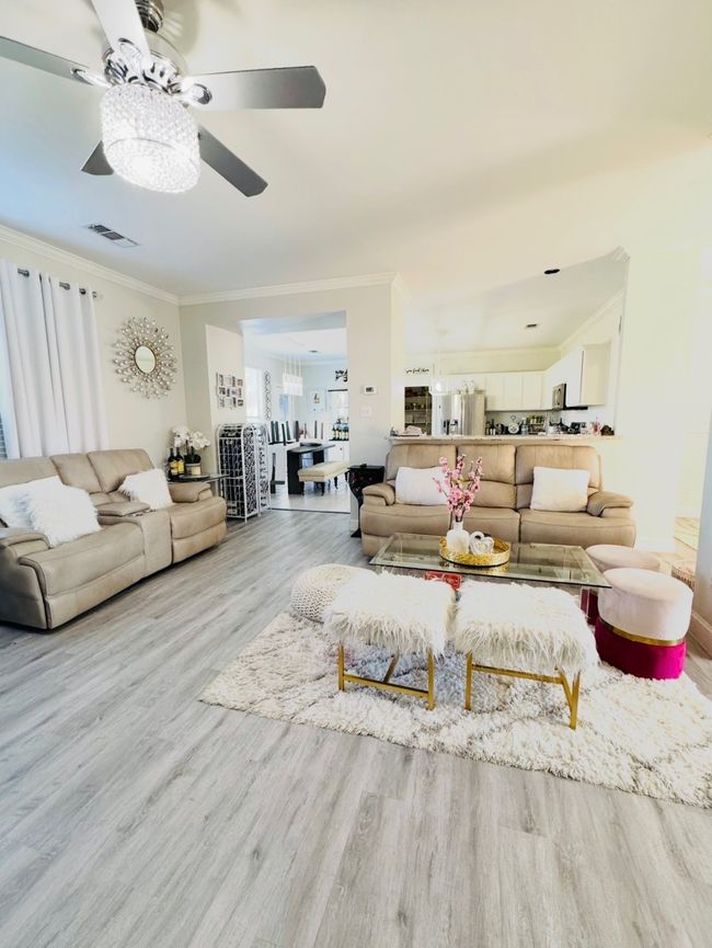 Living room with crown molding, a ceiling fan, wood finished floors, and a chandelier | Image 13