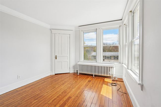Unfurnished room with crown molding, radiator heating unit, hardwood / wood-style floors, and baseboards | Image 20