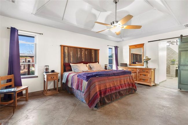 Bedroom with a barn door, a ceiling fan, visible vents, baseboards, and finished concrete floors | Image 13
