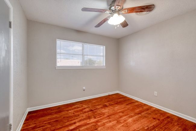 Bedroom 1 with a ceiling fan, a textured ceiling, baseboards, and wood finished floors | Image 14