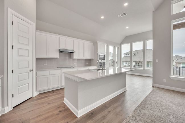 Kitchen featuring under cabinet range hood, white cabinetry, and light countertops | Image 9