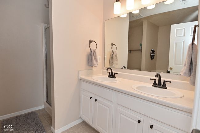 full bath with double vanity, a shower with shower door, tile patterned flooring, and baseboards | Image 42