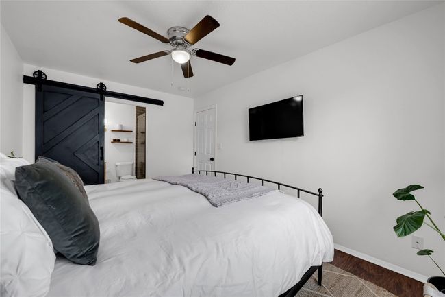 Bedroom featuring baseboards, a barn door, wood finished floors, and a ceiling fan | Image 19