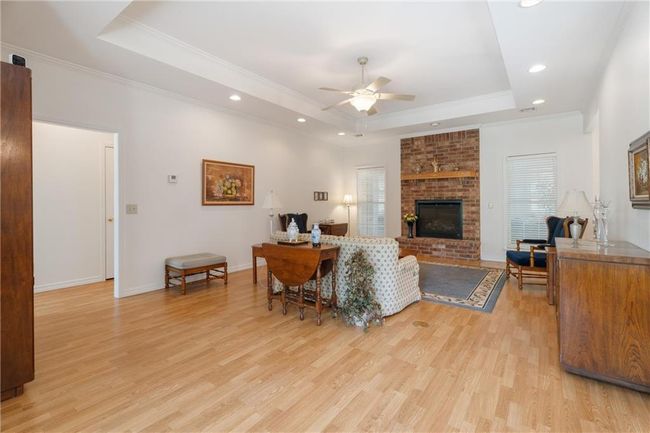 Living room with a raised ceiling, ceiling fan, a fireplace, recessed lighting, and light wood finished floors | Image 32