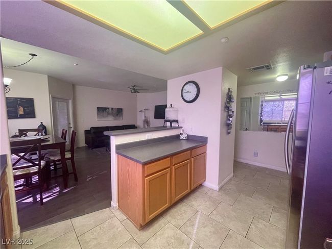 Kitchen with open floor plan, light tile patterned floors, freestanding refrigerator, dark countertops, and visible vents | Image 13