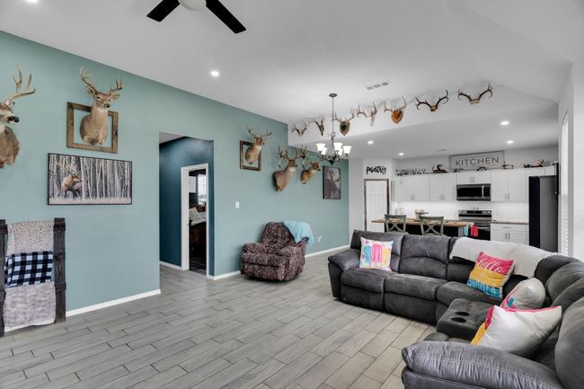 Living area featuring a chandelier, light wood-type flooring, a ceiling fan, recessed lighting, and baseboards | Image 10