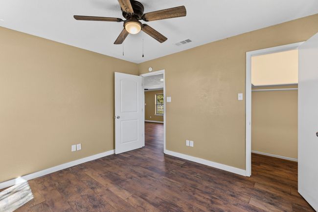Unfurnished bedroom with dark wood-type flooring, a ceiling fan, visible vents, and baseboards | Image 23