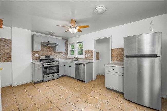 Unit #68 Kitchen featuring ceiling fan, tasteful backsplash, appliances with stainless steel finishes, and light tile patterned flooring | Image 9