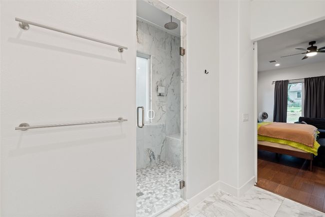 Bathroom featuring ensuite bath, a marble finish shower, marble look tile flooring, a ceiling fan, and baseboards | Image 18