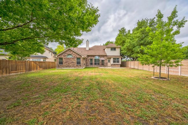 Rear view of property featuring a chimney, a patio, a fenced backyard, and a lawn | Image 27