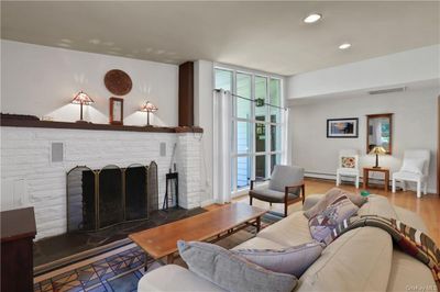 Living room with a fireplace, baseboard heating, and hardwood / wood-style floors | Image 2