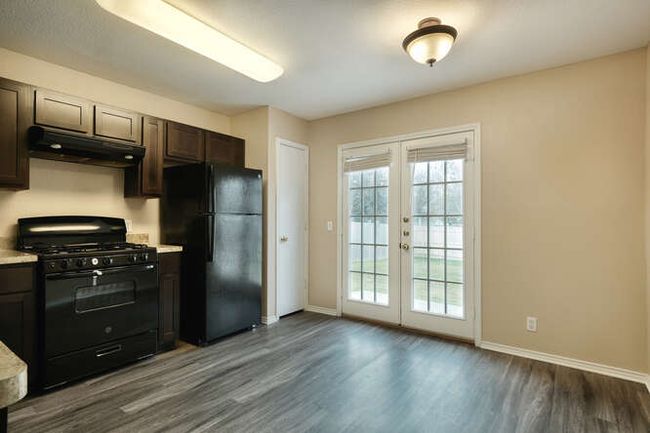 Kitchen featuring black appliances, under cabinet range hood, french doors, baseboards, and dark wood-style flooring | Image 4