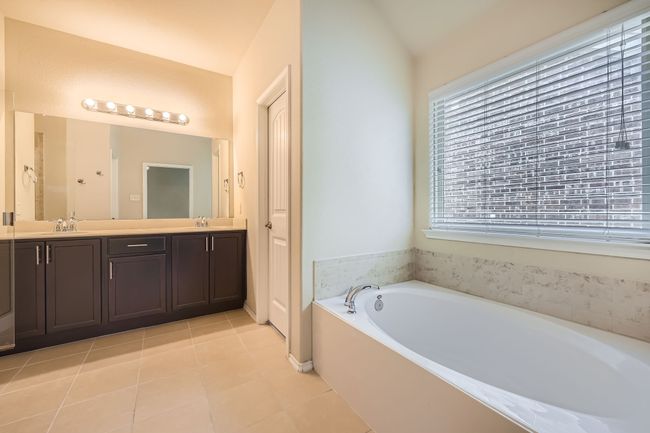 Full bath featuring double vanity, a bath, tile patterned flooring, and vaulted ceiling | Image 17